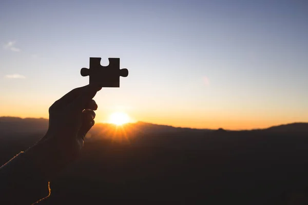 Silhouette of business woman hand holding  jigsaw puzzle piece against sunrise, Business solutions, target, success, goals and strategy concepts