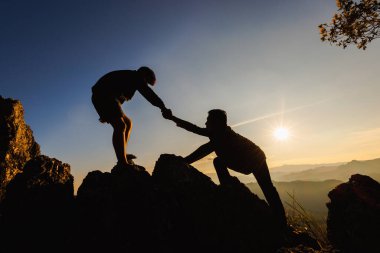  İki insanın dağa tırmanıp yardım ettiği siluetler. Yardım ve yardım kavramı.