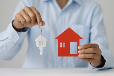 Oyuncak evi ve metal tuşları tutan kadın. Konut satın alma kavramı