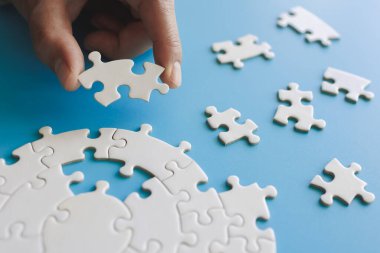 Yapboz ile güneş ışığı efektini birbirine bağlayan yakın el, iş çözümleri, başarı ve strateji kavramı