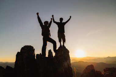 Başarılı iki adamın silueti dağın tepesinde duruyor. iş takım çalışması kavramı.