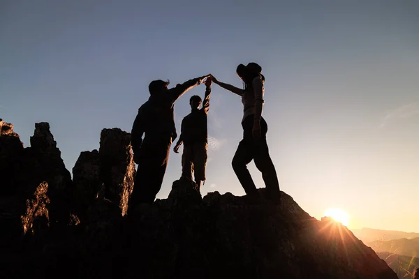 Silhouette of  happy teamwork hold hands up as a business successful, business victory, achieve business goal, Teamwork helping hand trust assistance.
