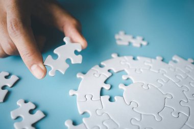 İnsanların elinde beyaz yapboz, doğru çözüm. Takım çalışması, çözme ve görevi tamamlama. Yapbozun son parçası. Yapboz parçaları monte ediliyor.