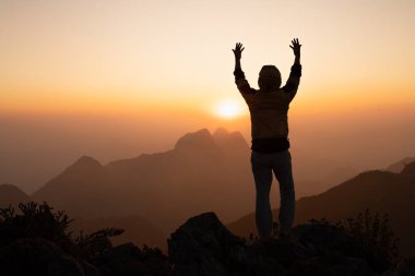 Bir adamın silueti gün doğumunda Tanrı 'ya inancı ve dine olan inancı ile el ele dua ediyor. Dua pozisyonu.