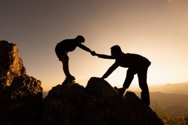 İki insanın dağa tırmanıp yardım ettiği siluetler. Yardım ve yardım kavramı. Yardım eli, spor eğitimi..