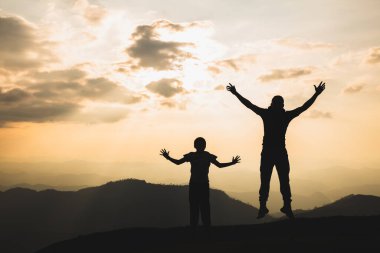 Güneş batarken kolları ve bacakları açık atlayan bir adamın silueti. Başarı konsepti. Özgürlük yolculuğu Seyahat, macera, mutluluk.