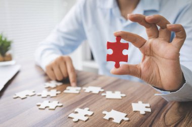 Yapboz parçalarını, iş çözümlerini, hedefleri, başarıyı, hedefleri ve strateji kavramını birleştiren kişi eli.