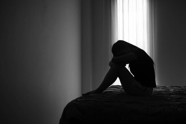 Silhouette of depressed woman sitting in bedroom Beset by health problems accumulated stress Relationship problems.
