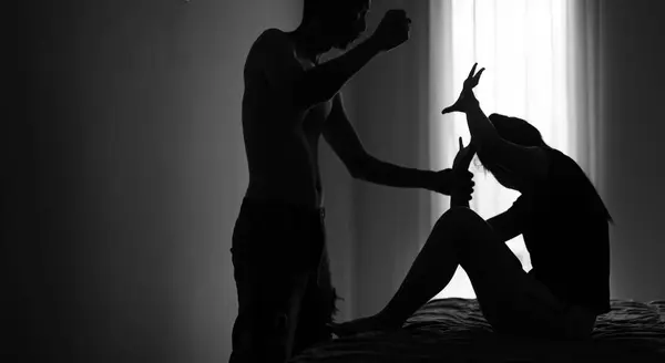 Silhouette of a man assaulting a defenseless woman. Concept of Stop Violence Against Women, Domestic Violence, Woman Victim of Violence.