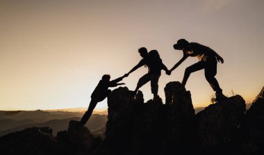 Silüet erkek ve kadın yürüyüşçüler dağ uçurumuna tırmanıyorlar. Yardım ve ekip çalışması konsepti. Bağımsız yürüyüş, başarı.