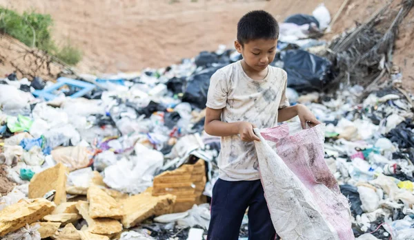 Poor children on the garbage dump and selecting plastic waste to sell, children not in school, poverty.