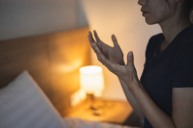 Hristiyan bir kadın yatak odasında dua ediyor, kadın elleri Tanrı 'ya dua ediyor, af diliyor ve iyiliğe inanıyor. Hristiyan hayatı, Tanrı 'ya dua etmek. Hristiyan hayatı kriz duası..