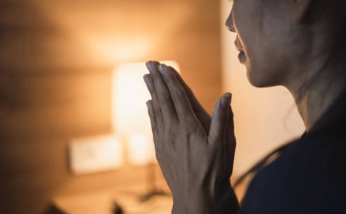 Hristiyan bir kadın yatak odasında dua ediyor, kadın elleri Tanrı 'ya dua ediyor, af diliyor ve iyiliğe inanıyor. Hristiyan hayatı, Tanrı 'ya dua etmek. Hristiyan hayatı kriz duası..