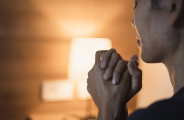 Hristiyan bir kadın yatak odasında dua ediyor, kadın elleri Tanrı 'ya dua ediyor, af diliyor ve iyiliğe inanıyor. Hristiyan hayatı, Tanrı 'ya dua etmek. Hristiyan hayatı kriz duası..
