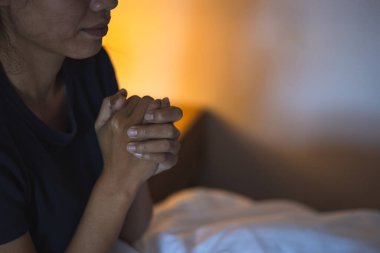 Hristiyan bir kadın yatak odasında dua ediyor, kadın elleri Tanrı 'ya dua ediyor, af diliyor ve iyiliğe inanıyor. Hristiyan hayatı, Tanrı 'ya dua etmek. Hristiyan hayatı kriz duası..