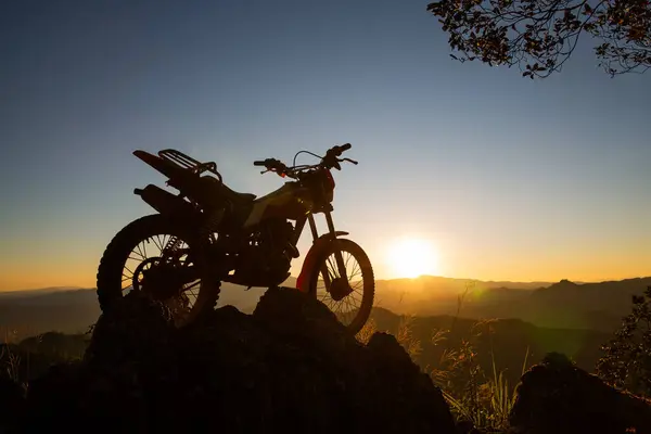 motocross bike against beautiful lights, silhouette of a  motocross motorcycle On top of rock high mountain at beautiful sunset, enduro motorcycle travel concept.