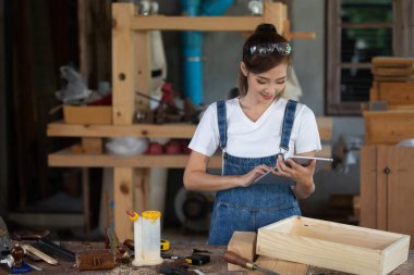 Genç bayan atölyede marangozluk eğitimi alıyor. Marangoz ahşap masada ekipmanla çalışıyor. Kadın bir marangozhanede çalışıyor..