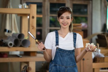 Genç bayan atölyede marangozluk eğitimi alıyor. Marangoz ahşap masada ekipmanla çalışıyor. Kadın bir marangozhanede çalışıyor..