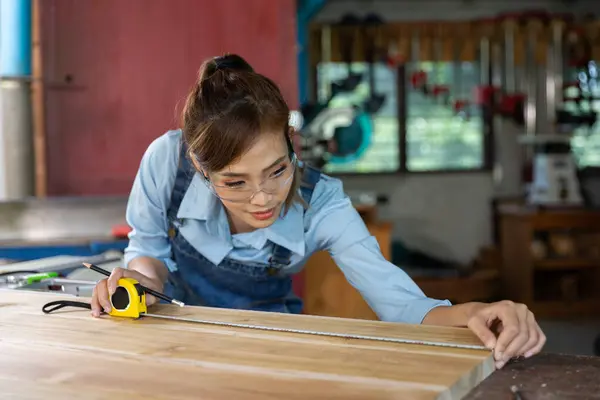 Young woman is training to be a carpenter in workshop. Carpenter working with equipment on wooden table. woman works in a carpentry shop.