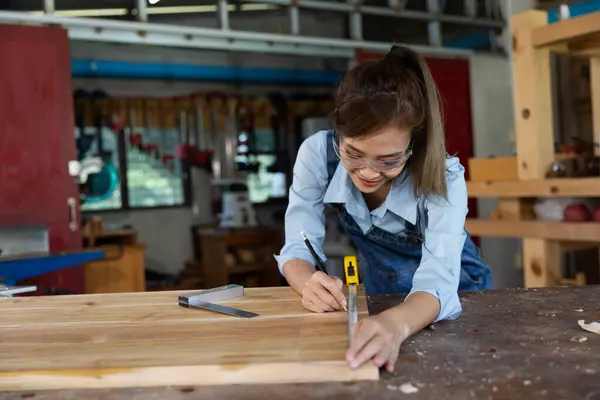 Young woman is training to be a carpenter in workshop. Carpenter working with equipment on wooden table. woman works in a carpentry shop.