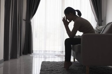 Evde depresyondan muzdarip bir insanın silueti koltukta yalnız başına oturan depresyonlu bir kadın karanlık odada üzgün ve endişeli hissediyor. İnsan streslidir..