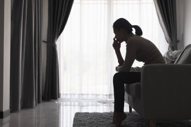 Evde depresyondan muzdarip bir insanın silueti koltukta yalnız başına oturan depresyonlu bir kadın karanlık odada üzgün ve endişeli hissediyor. İnsan streslidir..