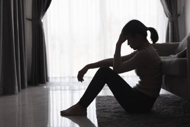 Evde depresyondan muzdarip bir insanın silueti koltukta yalnız başına oturan depresyonlu bir kadın karanlık odada üzgün ve endişeli hissediyor. İnsan streslidir..