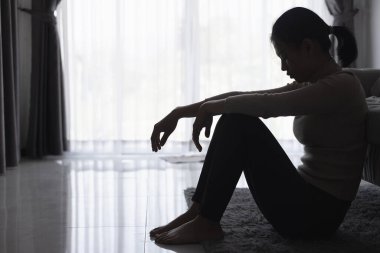 Evde depresyondan muzdarip bir insanın silueti koltukta yalnız başına oturan depresyonlu bir kadın karanlık odada üzgün ve endişeli hissediyor. İnsan streslidir..