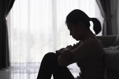 Evde depresyondan muzdarip bir insanın silueti koltukta yalnız başına oturan depresyonlu bir kadın karanlık odada üzgün ve endişeli hissediyor. İnsan streslidir..