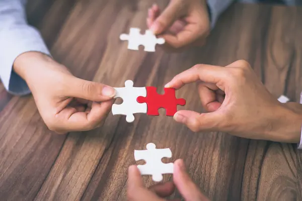 Hand put the last piece of jigsaw puzzle to complete the mission. Concept of connecting jigsaw pieces, problem solving, teamwork and success.