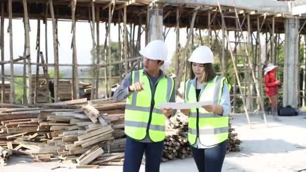 男性および女性の土木技術者は 建設中のプロジェクトを検査および分析する エンジニアリングと建築コンセプト — ストック動画