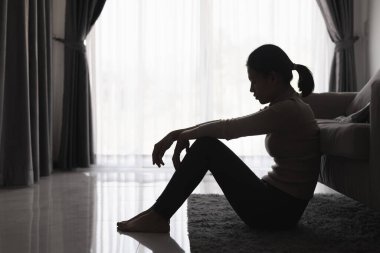 Evde depresyondan muzdarip bir insanın silueti koltukta yalnız başına oturan depresyonlu bir kadın karanlık odada üzgün ve endişeli hissediyor. İnsan streslidir..