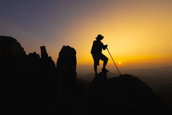 Silhouette of a Climber at the top of the rocky mountain at sunset, Man on top of mountain. Conceptual design. alone at the summit climber  successful climbers. Sport and active life.