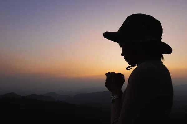 Silhouette of a women is praying to God on the mountain. Praying hands with faith in religion and belief in God on blessing background. Power of hope or love and devotion.