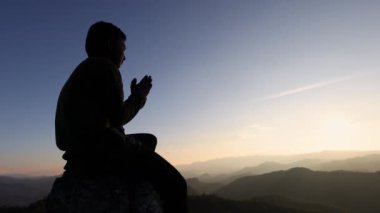 Dağdaki bir adamın silueti Güneş batıyor. Tanrıya şükretmek için dua ediyorum. Tanrı daha iyi bir hayat ve Hıristiyan kriz dualarını kutsasın..