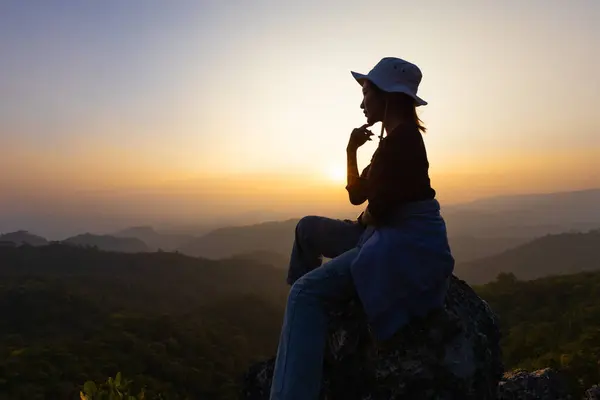 person on top of mountain, Silhouette of Young woman sitting on a rock  looking to the horizon.