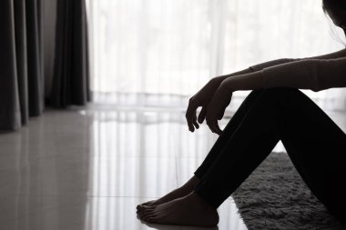 Bunalımlı kadın, depresyondaki genç kız silueti karanlık odada tek başına oturuyor. Siyah beyaz fotoğraf.