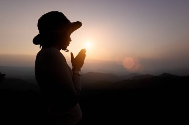 İnsan elleri avuçlarını açıp ibadete başlar. Dua eden kadının silueti sabah Tanrı 'ya ibadet eder, gökyüzünün doğuşuyla birlikte. Tanrı, Katolik tövbesine yardım ediyor..