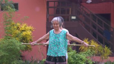 Asyalı kadın fizyoterapist yaşlı bir insana fizik tedavi uyguluyor ve evinde egzersiz yapıyor. Sinir ağrısını tedavi etmek ve yaşlı kadınların sağlığıyla ilgilenmek.