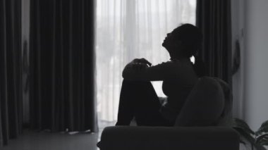 Stresli ve depresyondan muzdarip bir kadının silueti. Endişeli genç kadın umutsuzluk ve stres. Yalnız ve mutsuz kadınlar sosyal kurbanlardır. Evde yalnızlık gençliği.