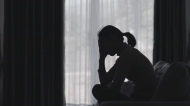 Stresli ve depresyondan muzdarip bir kadının silueti. Endişeli genç kadın umutsuzluk ve stres. Yalnız ve mutsuz kadınlar sosyal kurbanlardır. Evde yalnızlık gençliği.