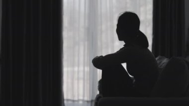 Stresli ve depresyondan muzdarip bir kadının silueti. Endişeli genç kadın umutsuzluk ve stres. Yalnız ve mutsuz kadınlar sosyal kurbanlardır. Evde yalnızlık gençliği.