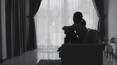 Stresli ve depresyondan muzdarip bir kadının silueti. Endişeli genç kadın umutsuzluk ve stres. Yalnız ve mutsuz kadınlar sosyal kurbanlardır. Evde yalnızlık gençliği.