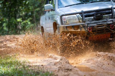 Arabalar off-road yollarında koşuyor ve doğal yollara çamur sıçrıyor. Çamurlu yolda off-road yolculuğu. Offroad seyahat ve sürüş konsepti, çamurlu bir yol ile kırsal bir araziye yakın tekerlek.