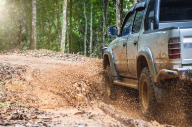 Çamurlu yolda off-road yolculuğu. Offroad seyahat ve sürüş kavramı yağmur mevsiminde açık hava macerası ve seyahatte. Çamurlu araba lastiklerine sıcak renklerle yaklaşın..