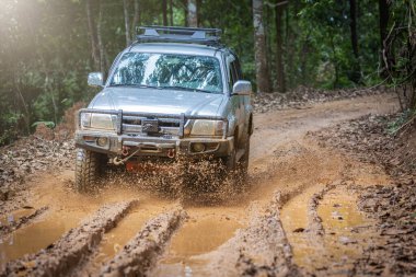 Çamurlu yolda off-road yolculuğu. Offroad seyahat ve sürüş kavramı yağmur mevsiminde açık hava macerası ve seyahatte. Çamurlu araba lastiklerine sıcak renklerle yaklaşın..