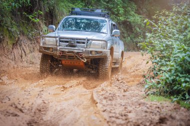 Çamurlu yolda off-road yolculuğu. Offroad seyahat ve sürüş kavramı yağmur mevsiminde açık hava macerası ve seyahatte. Çamurlu araba lastiklerine sıcak renklerle yaklaşın..