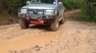 Arabalar off-road yollarında koşuyor ve doğal yollara çamur sıçrıyor. Çamurlu yolda off-road yolculuğu. Offroad seyahat ve sürüş konsepti, çamurlu bir yol ile kırsal bir araziye yakın tekerlek.