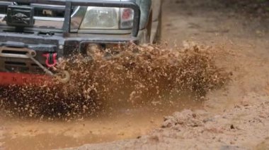 Arabalar off-road yollarında koşuyor ve doğal yollara çamur sıçrıyor. Çamurlu yolda off-road yolculuğu. Offroad seyahat ve sürüş konsepti, çamurlu bir yol ile kırsal bir araziye yakın tekerlek.