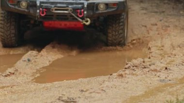 Arabalar off-road yollarında koşuyor ve doğal yollara çamur sıçrıyor. Çamurlu yolda off-road yolculuğu. Offroad seyahat ve sürüş konsepti, çamurlu bir yol ile kırsal bir araziye yakın tekerlek.